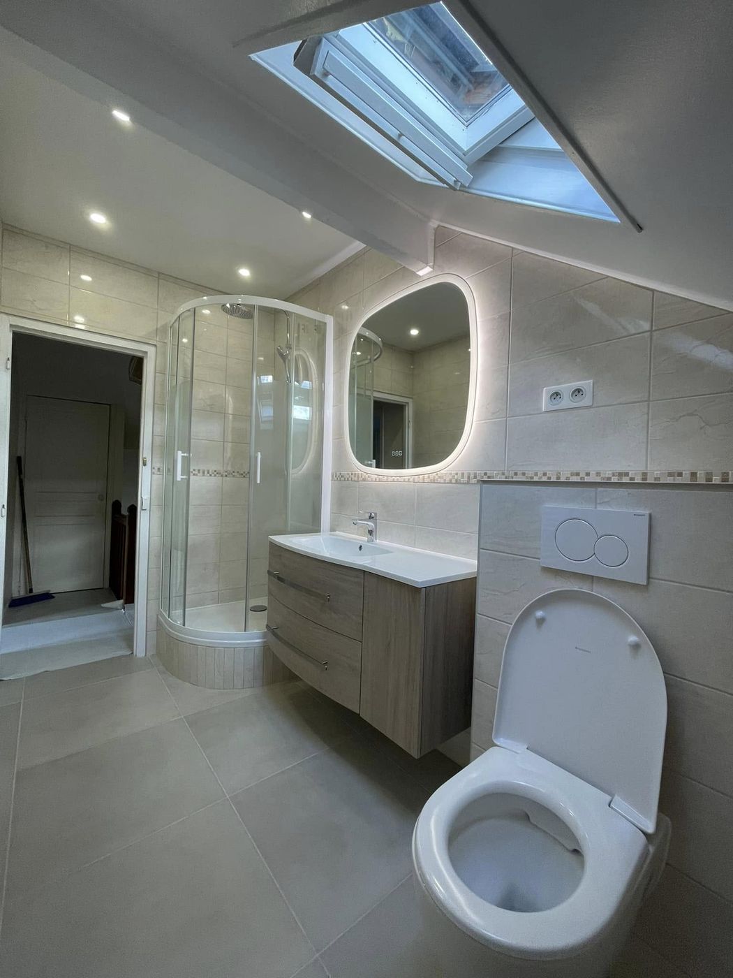Salle de bain sous combles : cabine de douche d'angle, meuble vasque et miroir lumineux